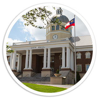 Front-facing view of Roswell city hall on a bright sunny day with the Georgia flag blowing in the wind